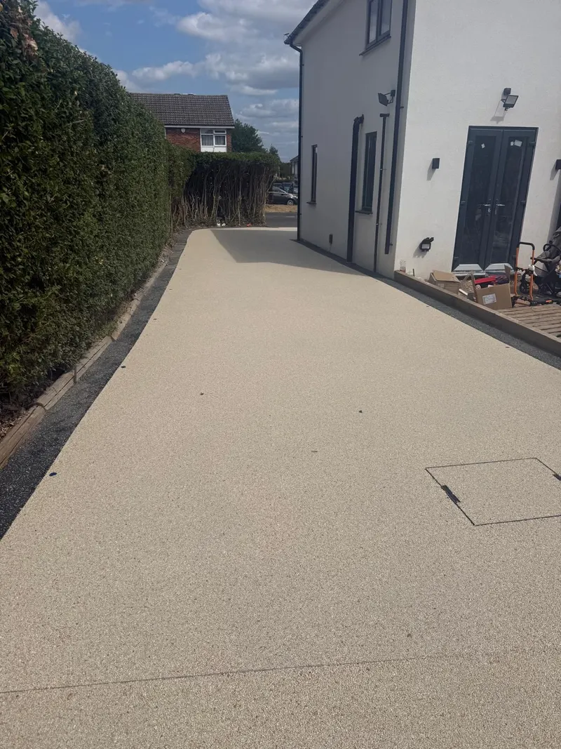 Long resin bound driveway beside a rendered house